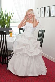 Beautiful blonde bride in white dress in interior