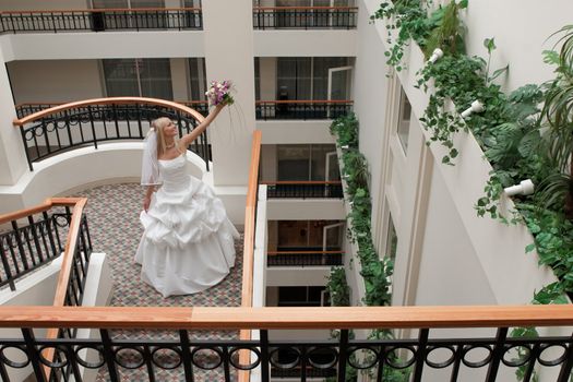 Beautiful blonde bride with bunch of flowers in the gallery