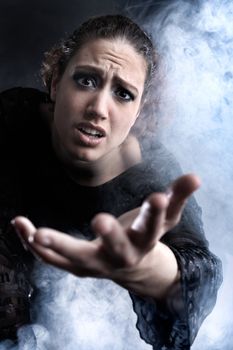 Portrait of a woman with long curly hair begging in smoke