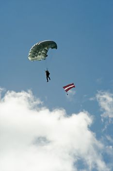 Parachute with Latvian flag on cloudy sky background