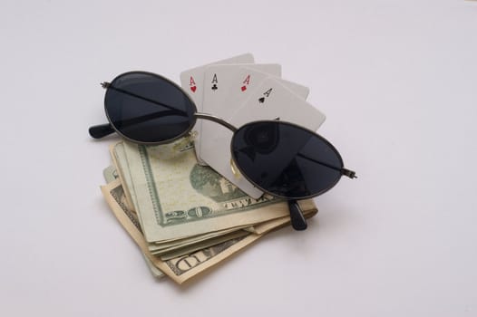 Four aces sitting on a dollar fold with sunglasses on an isolated background