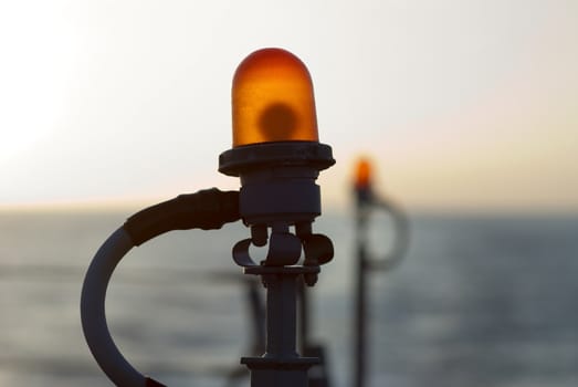Two orange signal lights on a US Destroyer shot with shallow depth of field at dusk.