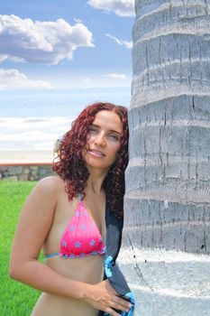 Pretty young woman standing next to palm tree