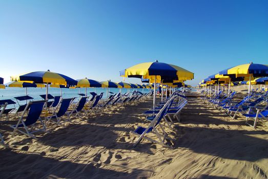 Empty beach with umbrellas and sea shortly after the sunrise