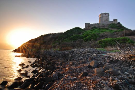 Ancient Sardinian castle on the coast during the sunrise