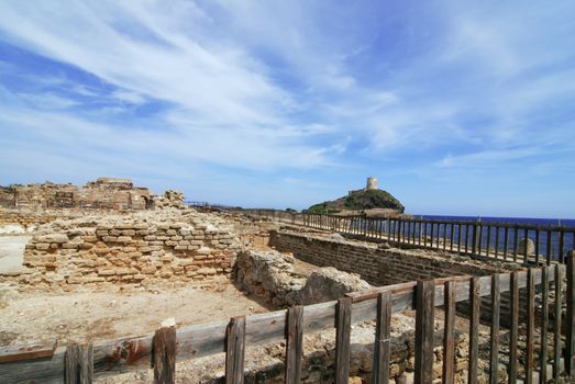 Ancient ruins at Nora and Sardinian lighthouse with fence