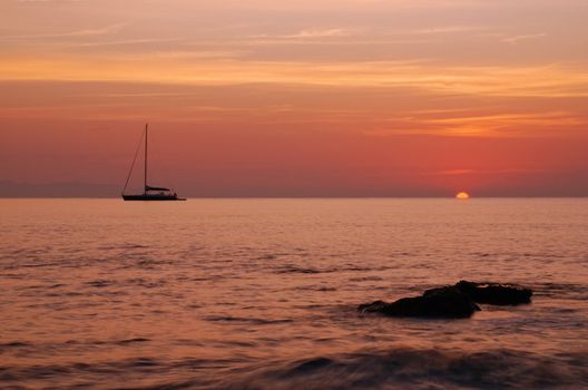 Sailing boat silhouette and sunrise - sun is just being born from the sea