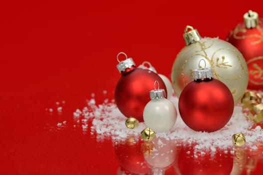 Red and white baubles with snow and jingle bells on red background