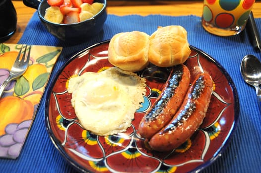 Breakfast with sausage, eggs, and dinner rolls.