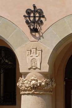 Symmetrical arches with pillar support. Krakow emblem made in stone.
