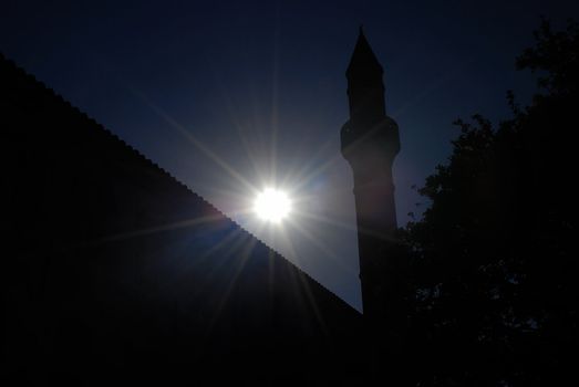 Islamic minaret tower and setting sun with diagonal architectonic elements