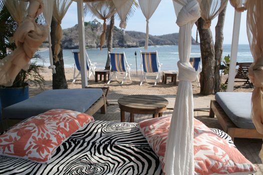 pergola and chairs on beach under palm tree in mexico