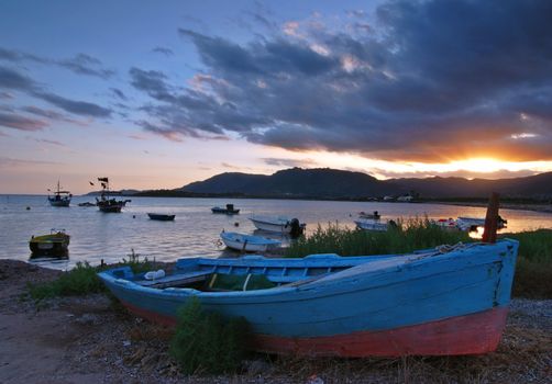 Beautiful sunset over harbor with a ship detail with dramatic sky on Sardinia