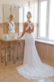 Beautiful blonde bride looking in the miirror.