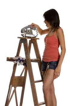 teenage girl standing on ladder slamming an old rotary phone 