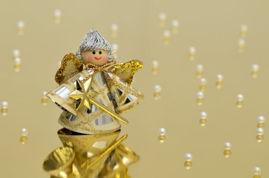 Vintage handmade angel decoration on glossy golden background with pearls