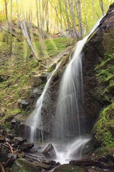 Beautiful waterfall in the forest with sunbeans through the trees.