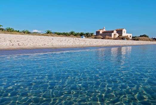 Nice white beach with blue sea and a church on Sardinia