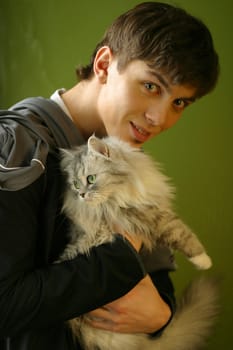 The young man covers a kitten on a green background