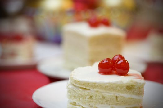 Delicious heart shaped frosted cake topped with cherries