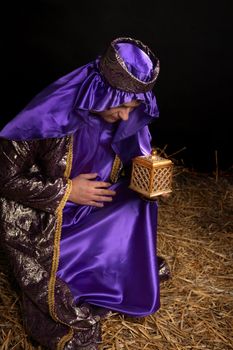 Wiseman from the east, bowing on bended knee and holding a gift of golden box filled with fine frankincense resin.
