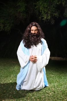 Jesus on knees praying earnestly in the Garden of Gethsemane.