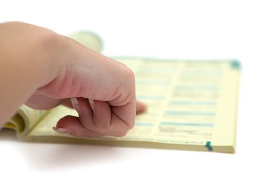 Female hand pointing on a yellow page. Shallow depth of field. White background.