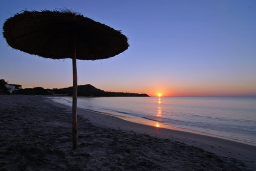 Umbrella silhouette on the beach during the sunrise