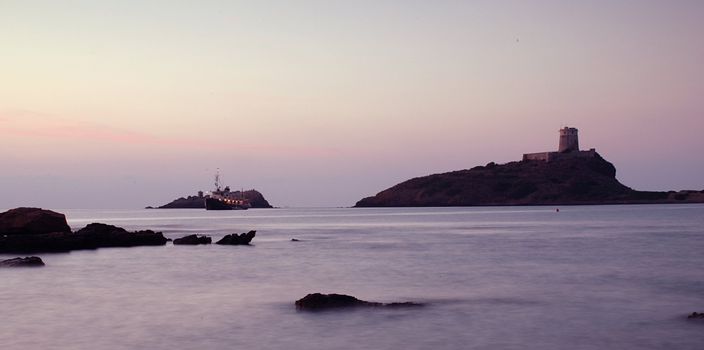 Sunrise in Sardinia with lighthouse and rocks