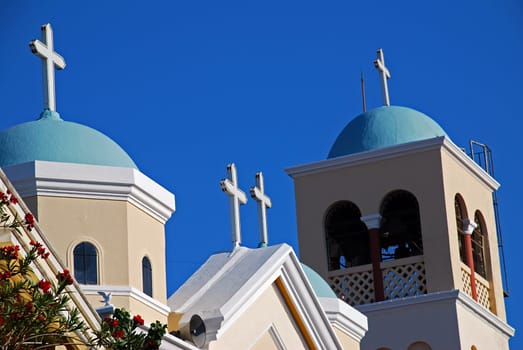 Blue cupolas of Greek orthodox church with red hibiscus tree
