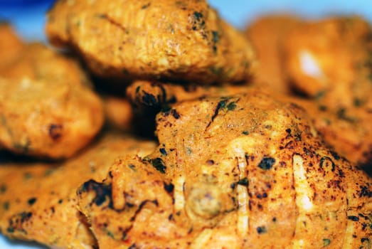 A close up photograph of chicken curry pieces on a blue plate