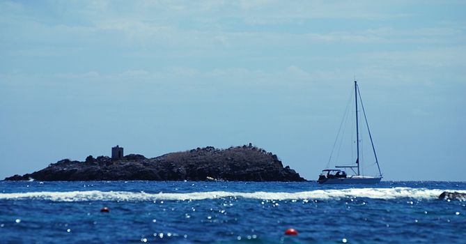 Small yacht is docking near the island with a shrine