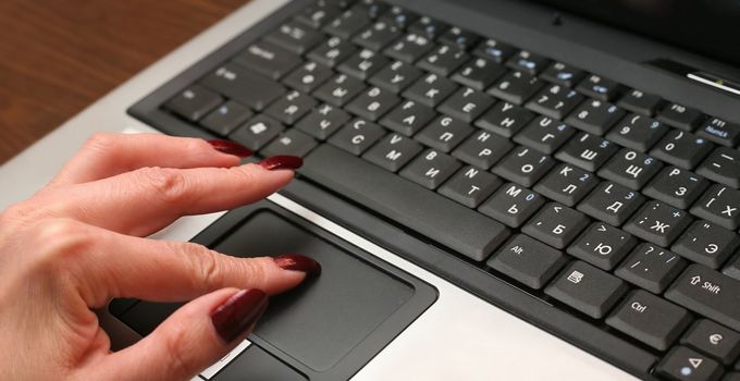 A woman's hand typing on a laptop