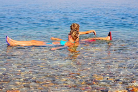 Woman And Boy Relaxing In Dead Sea Laying On Water Surface