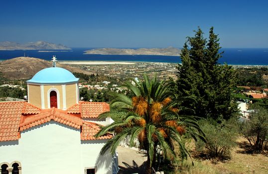 Greek orthodox church, lantern and palm with a view at sea