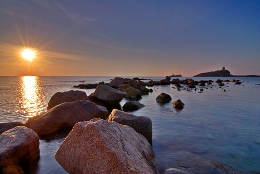 Sunrise in Sardinia with lighthouse and stone pier