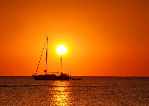 Sailing boat silhouette and golden sunset over the ocean