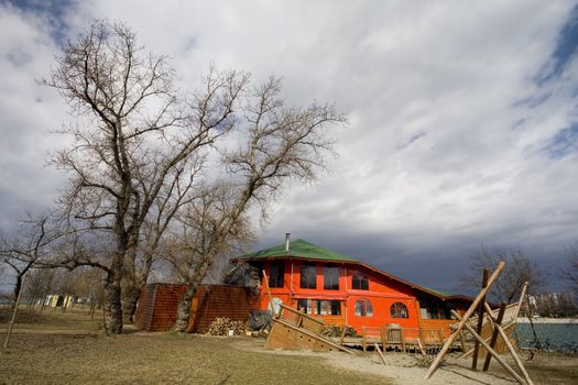 House near lake with tree and stormy clouds