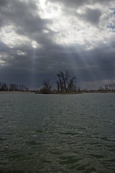 Rays of light comming through cloud over lake with island