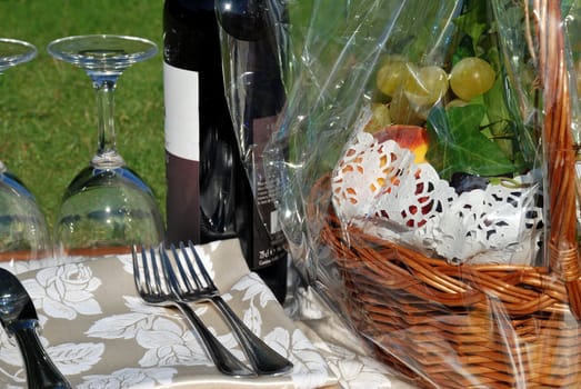 Wine still life on grass with basket of fruits and glasses