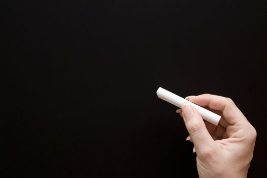 Female teacher holding a piece of chalk.