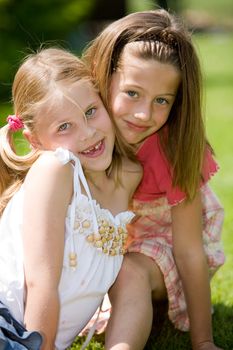 Two young girls posing together outdoors on a sunny day