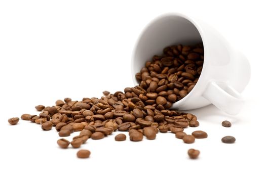 White cup and coffee beans. Shallow depth of field. White background.