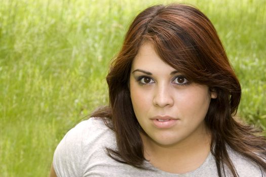 A young puerto rican woman over a background of green grass - plenty of copy space.