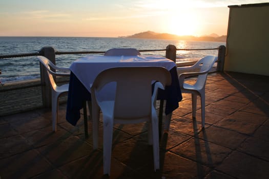 Restaurant table overlooking ocean at sunset