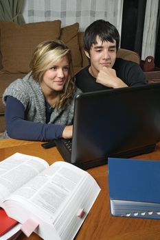Two students and friends doing their homework using their laptop.

