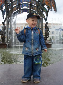 The happy boy costs at a fountain and smiles  