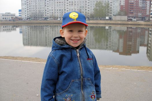 The smiling boy costs near a city pond