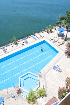 Beautiful blue pool surounded by plants and lounge chairs