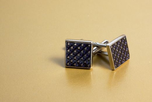 stainless steel cufflinks on the gold background